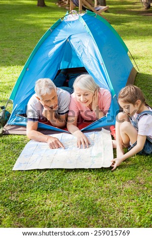 Grandparents with granddaughter studying map at campsite in park