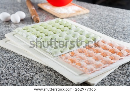 Uncooked ravioli pasta arranged on cutting board at countertop in commercial kitchen