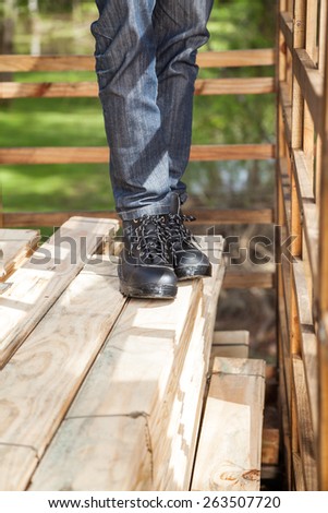Low section of male construction worker standing on stacked wooden planks at site