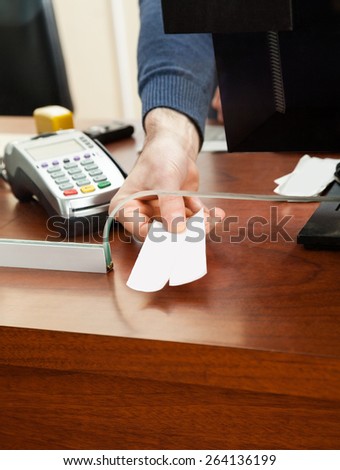 Cropped image of male worker holding tickets at box office counter