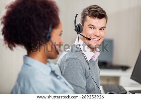 Male customer service representative talking with female colleague in office
