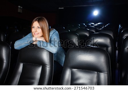 Beautiful woman leaning on seat while watching movie at cinema theater