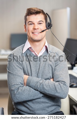 Portrait of confident male customer service representative with arms crossed sitting in office