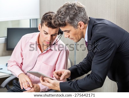 Manager and male customer service agent using digital tablet together in office