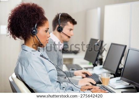 Side view of female customer service representatives with colleague working in call center