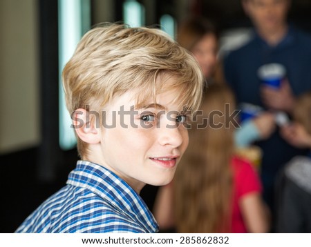 Portrait of cute boy at cinema with family in background