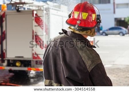 Rear view of male firefighter spraying water at fire station