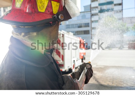 Side view of male firefighter spraying water while practicing at fire station