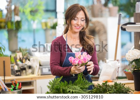 Happy florist making bouquet of pink roses in flower shop