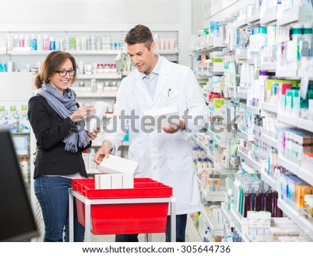 Smiling male chemist showing medicines to female customer in pharmacy