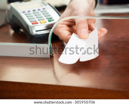Cropped image of male worker\'s hand holding tickets at box office counter