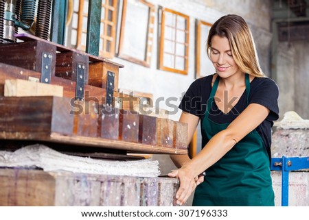 Smiling mid adult female worker drying papers using press machine in factory