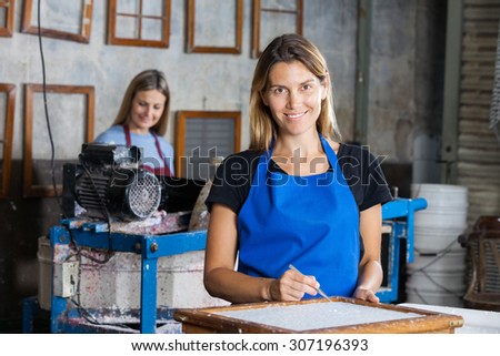 Portrait of confident female worker using tweezers to clean paper on mold in factory