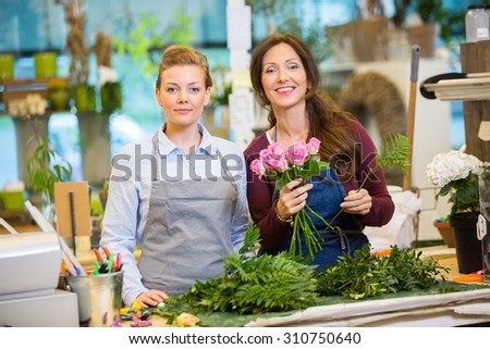 Portrait of happy florists making bouquet of pink roses in flower shop