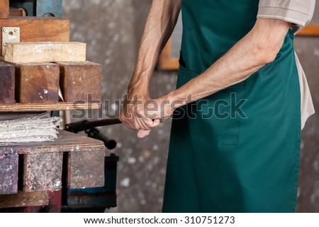 Midsection of male worker using paper press machine in factory
