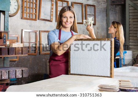 Portrait of happy mid adult female worker holding mold with paper in factory