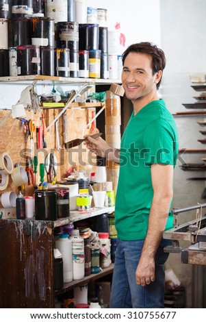 Portrait of confident man holding brush in paper factory