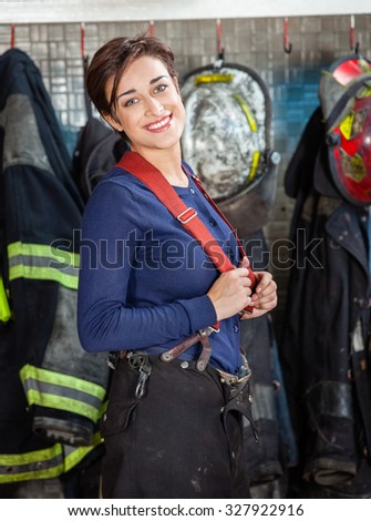Portrait of happy young firewoman standing at fire station