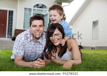 Portrait of cheerful family lying down on grass in front of house