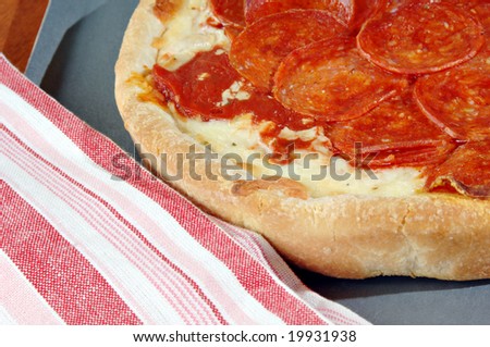 Deep dish pepperoni pizza with a red and white striped dish towel.