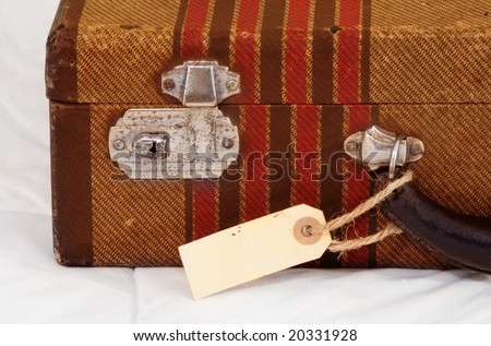 Vintage suitcase with a blank luggage tag or label.