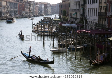 VENICE-AUGUST 18: Gondoliers ride gondola on the Grand Canal in Venice on August 18, 2013. Gondola is one of the symbols of Venice and major mode of touristic transport in Venice, Italy.