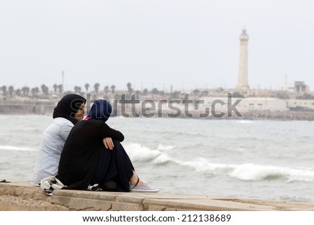 CASABLANCA, MOROCCO - JULY 23: Local people sitting at the pavement near the King Hassan II Mosque on July 23, 2014 in Casablanca, Morocco.Casablanca is the industrial center of the country.