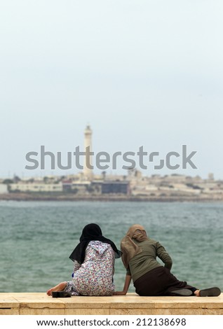 CASABLANCA, MOROCCO - JULY 23: Local people sitting at the pavement near the King Hassan II Mosque on July 23, 2014 in Casablanca, Morocco.Casablanca is the industrial center of the country.