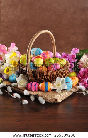 Easter basket with many painted easter eggs, narcissus and catkin