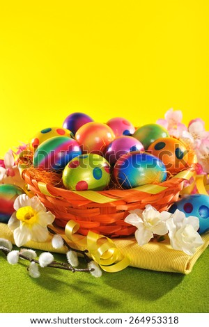 Colorful easter basket with painted easter eggs, narcissus and catkin