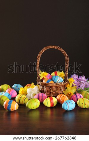 many painted easter eggs with easter basket and hyacinth in front of brown background