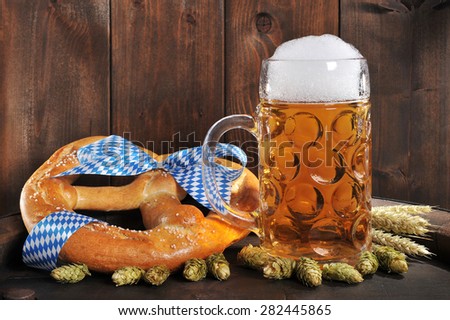 original bavarian Oktoberfest big soft pretzel with beer mug, hops and wheat on old beer barrel