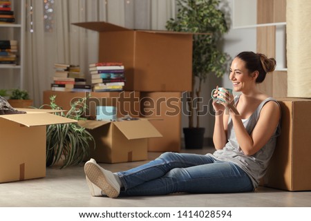 Happy tenant resting drinking coffee moving home sitting on the floor in the night Foto stock © 
