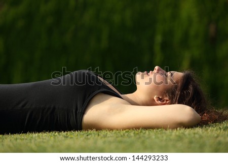 Attractive woman relaxed lying on the grass with a dark background