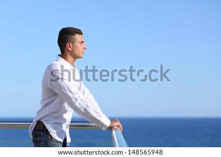 Handsome man looking at the horizon with the sea and a blue sky in the background