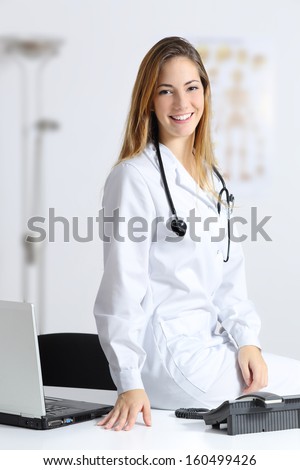 Beautiful female doctor sitting on the desk of her consultation