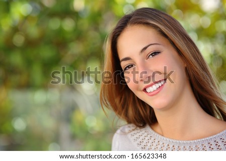 Beautiful woman facial with a perfect white smile outdoor with a green background