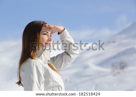 Hiker woman looking forward in the snowy mountain with her hand on forehead
