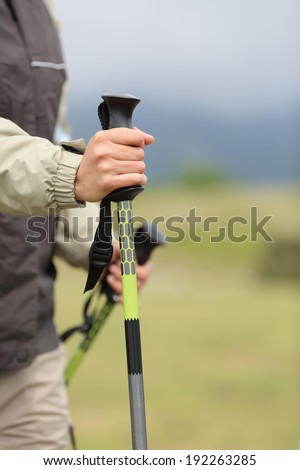 Close up of a hiker hands holding a hiking pole while walking in the mountain