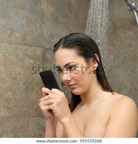 Teenager girl in the shower obsessed with the smart phone under a water jet