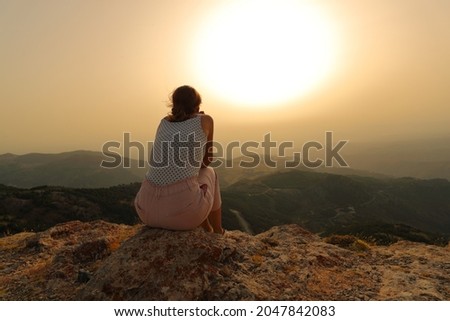 Back view portrait of a woman alone contemplating sunset in the mountain Foto stock © 