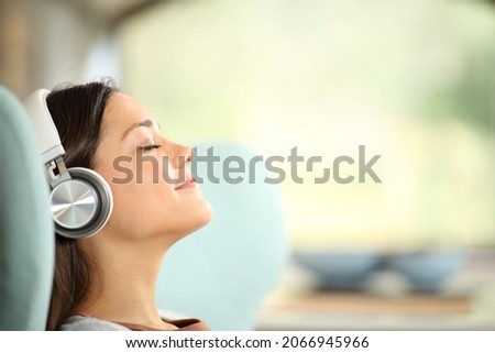 Side view portrait of a relaxed woman listening to hifi music sitting at home