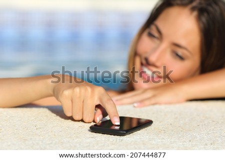 Close up of a happy woman in vacations texting in a smart phone bathing in a swimming pool with water in the background