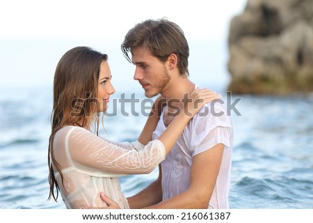 Profile of a young couple in love looking each other ready to kiss bathing in the sea