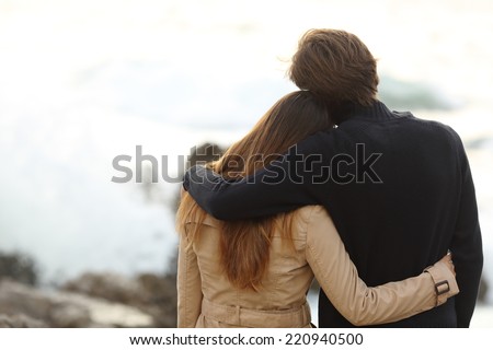 Back view of a couple cuddling in winter isolated in white above