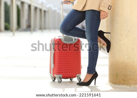 Close up of a tourist woman legs waiting with a suit case in an airport or station