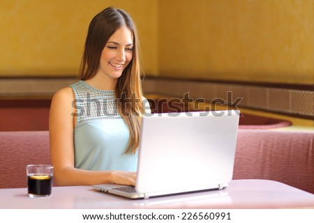 Happy girl working with a laptop in a restaurant interior