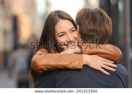 Portrait of a happy couple hugging in the street with the woman face in foreground