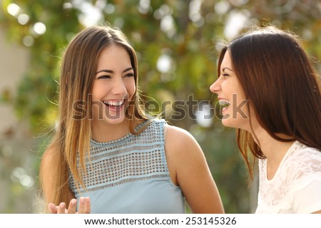 Happy women talking and laughing in a park with a green background