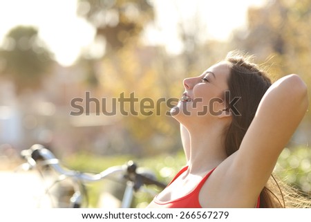 Back light of a woman breathing fresh air and relaxing in a park in spring or summer
